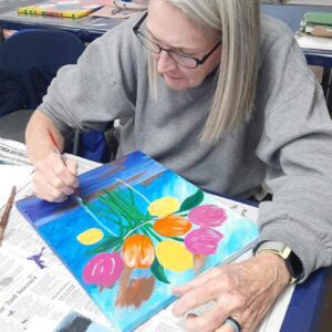 A lady painting flowers with paint brush